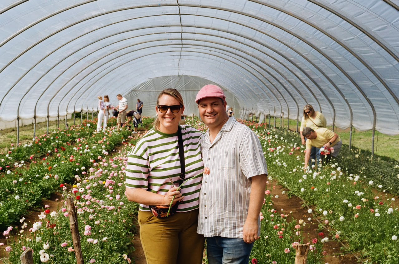 Two smiling church members in a flower tunnel